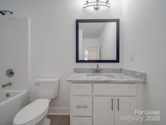 a bathroom with a toilet sink vanity and mirror