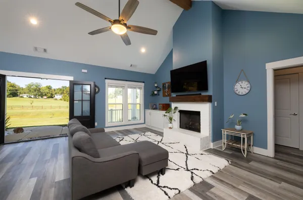 a living room with furniture a fireplace a flat screen tv and a large window