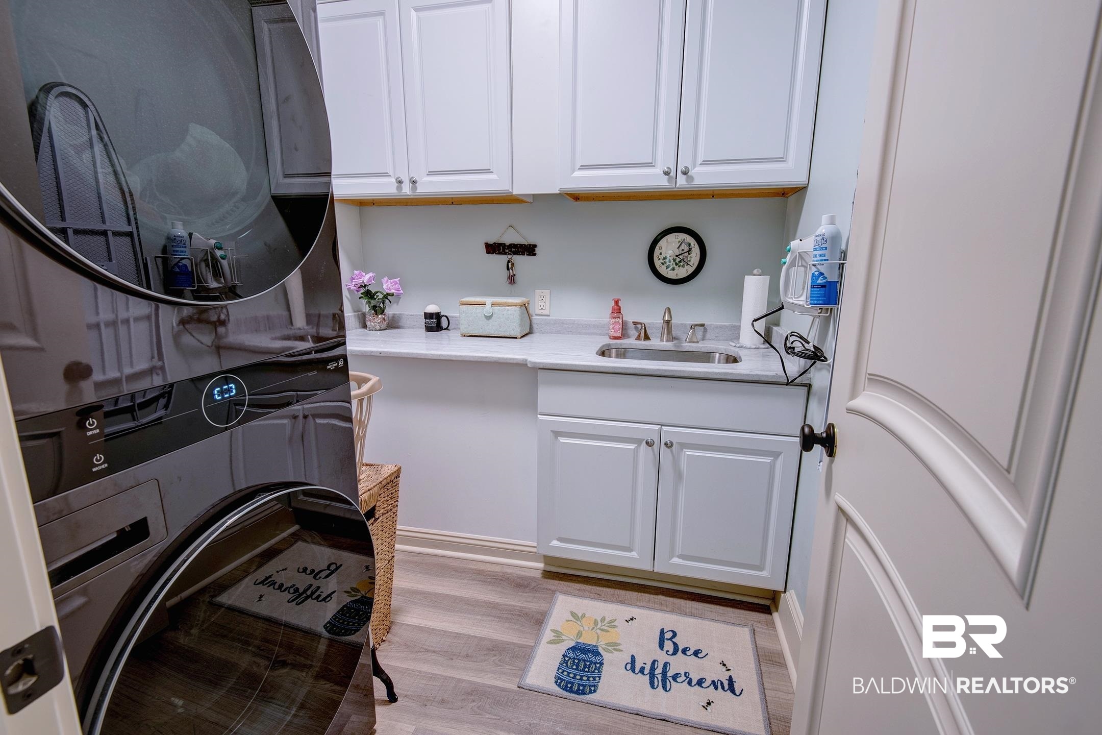 9357 Lakeview Drive Foley, AL 36535 - Photo 54 of 68 Laundry room featuring wood-finish flooring, white cabinetry, a built-in sink, and a countertop workspace