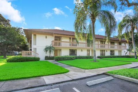 a view of a white house with a big yard and palm trees