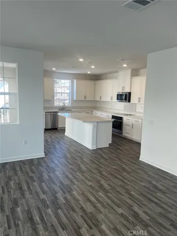 a large kitchen with kitchen island a sink dishwasher a stove and white cabinets with wooden floor