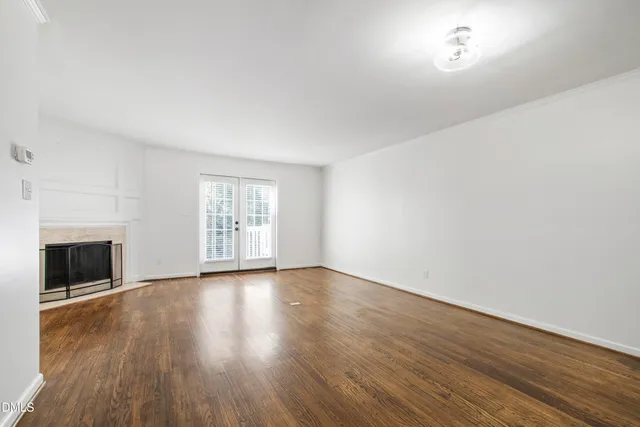 an empty room with wooden floor fireplace and windows