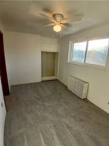 en empty room with windows and ceiling fan