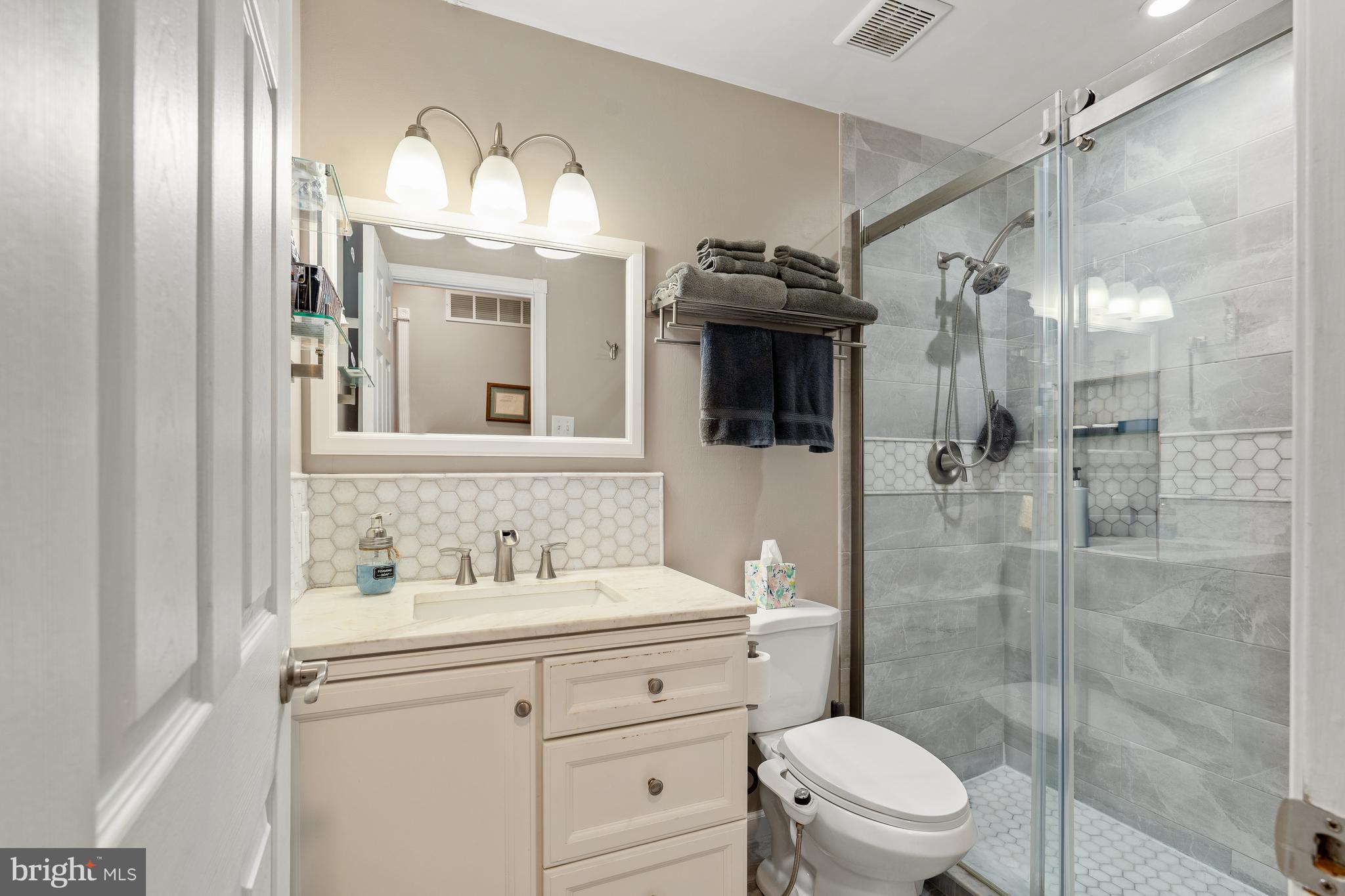26 Southbridge Road Bear, DE 19701 - Photo 25 of 29 a bathroom with a toilet a sink a glass door a shower and a mirror