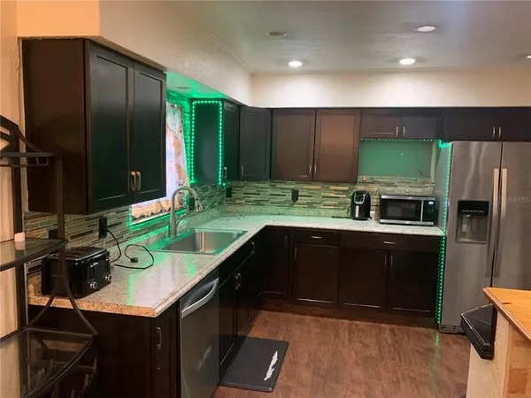 a kitchen with kitchen island granite countertop a sink refrigerator and cabinets