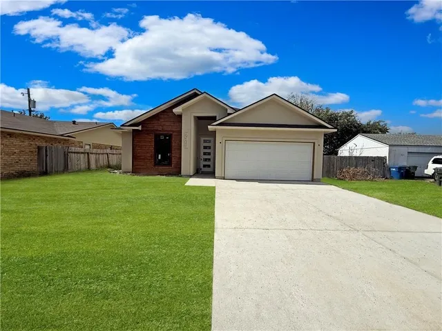 a front view of a house with yard and a tree