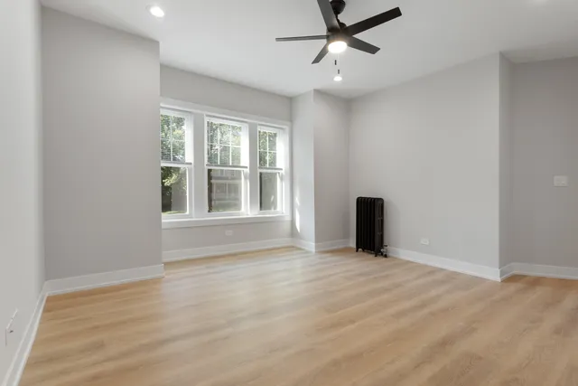 a view of an empty room with a window and wooden floor