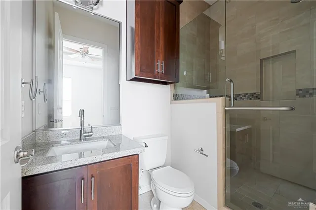 a bathroom with a granite countertop toilet sink and mirror