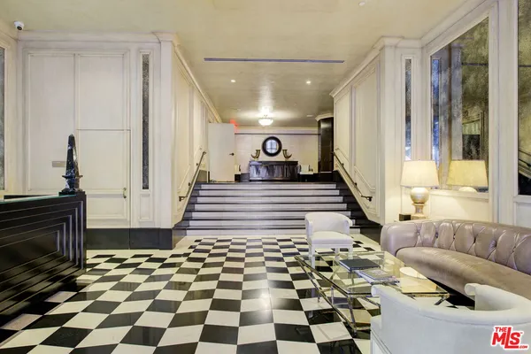 a living room with a black white checkered floor with couches chair and a coffee table