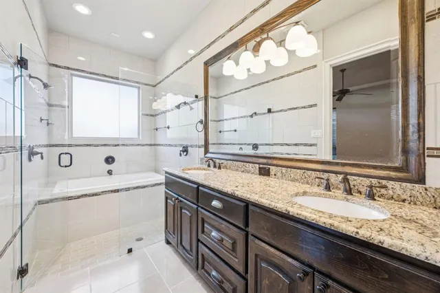 a bathroom with a granite countertop double vanity sink a mirror and a bathtub