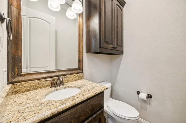 a bathroom with a granite countertop sink a toilet and mirror