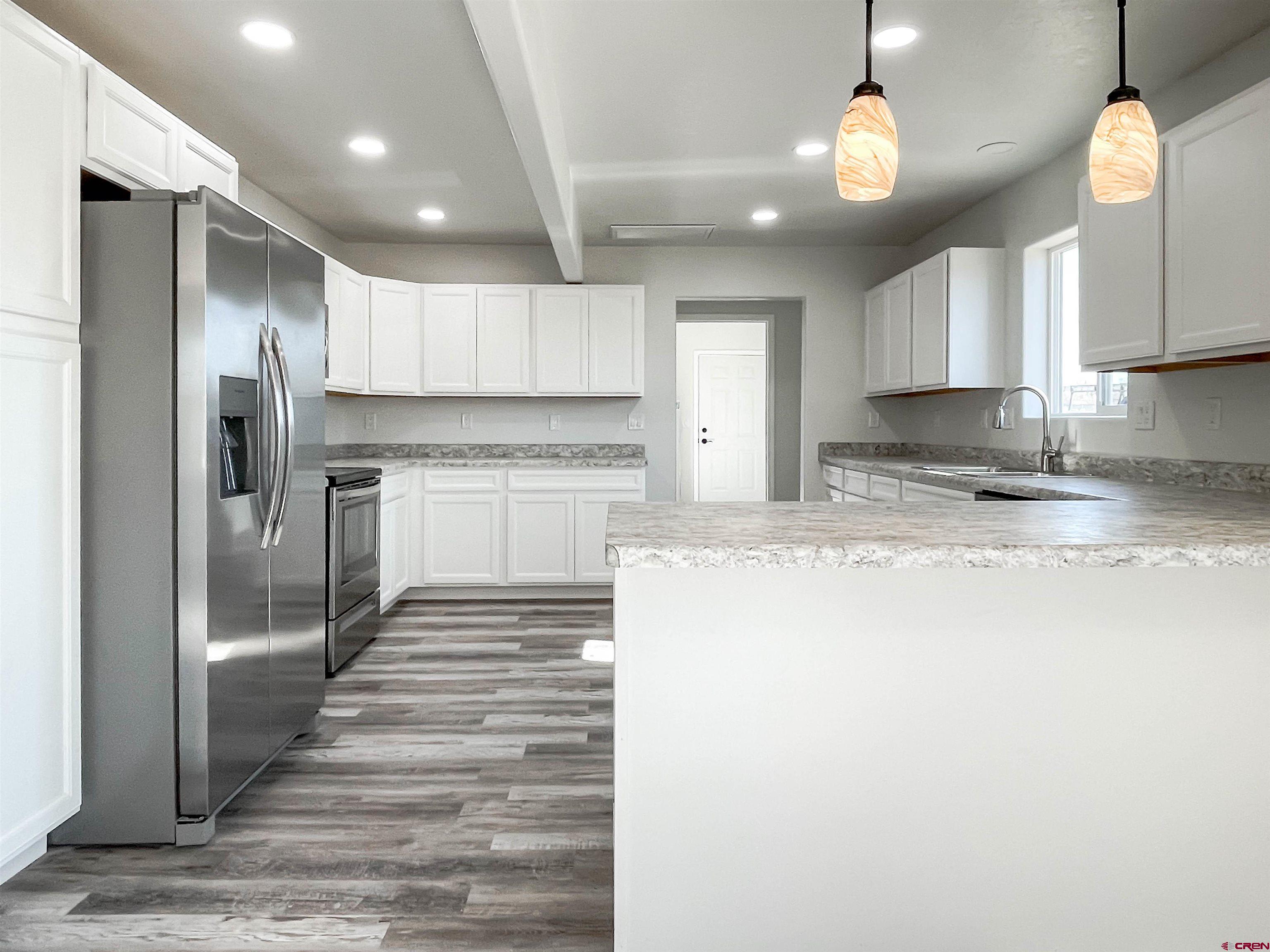 554 A Street Delta, CO 81416 - Photo 16 of 33 a kitchen with stainless steel appliances granite countertop a refrigerator a stove and a sink with wooden floor