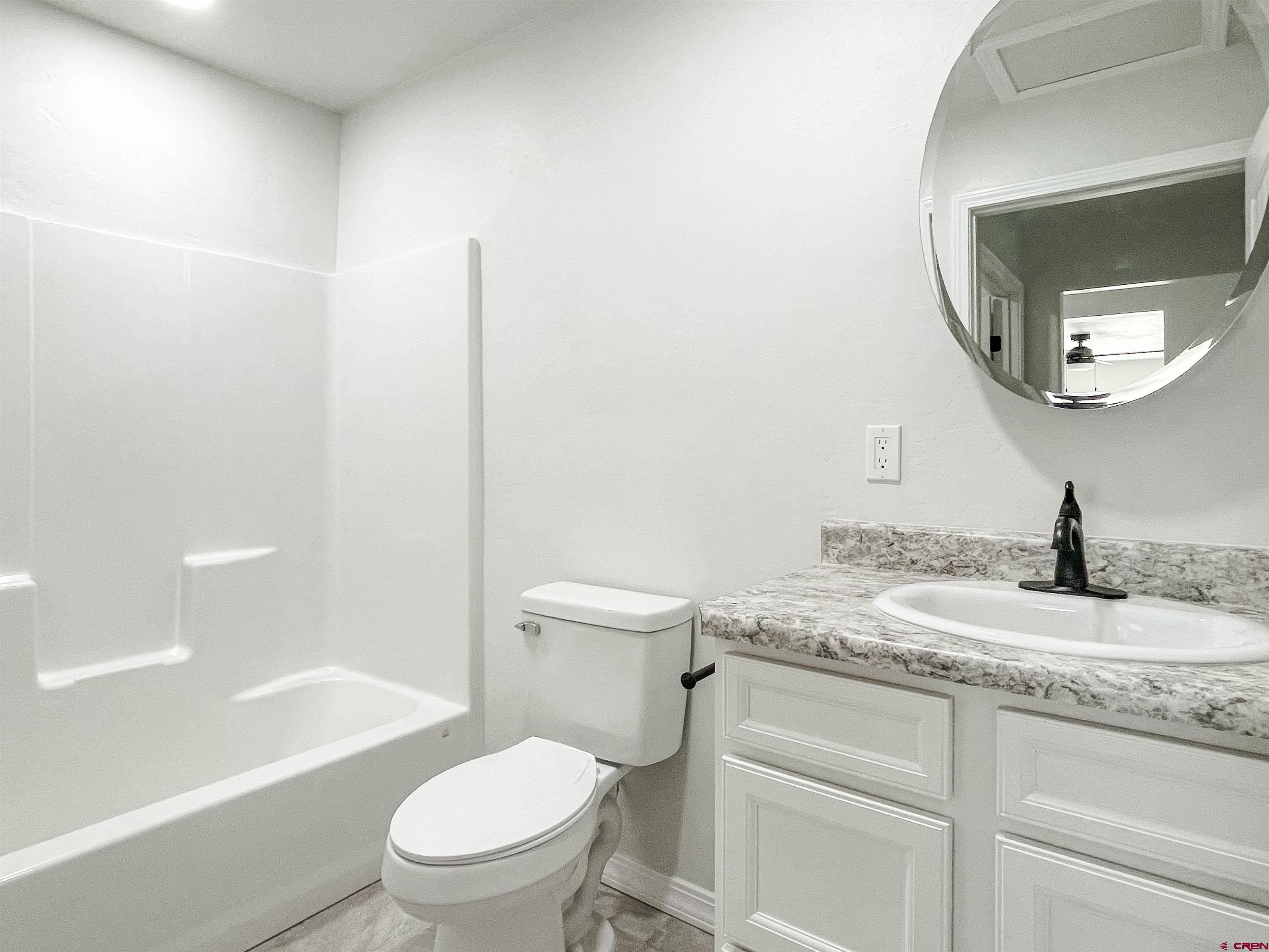 554 A Street Delta, CO 81416 - Photo 30 of 33 a bathroom with a granite countertop toilet a sink and a mirror