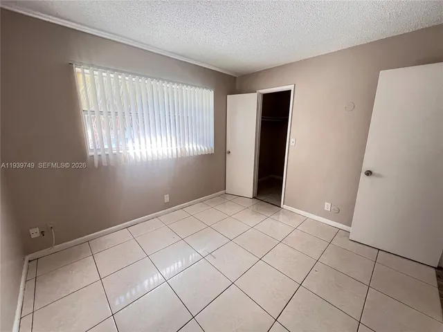 a view of an empty room with window and closet area