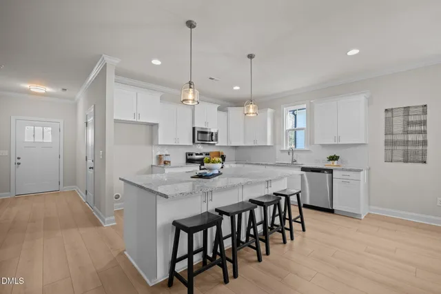 a kitchen with kitchen island a dining table chairs and white cabinets