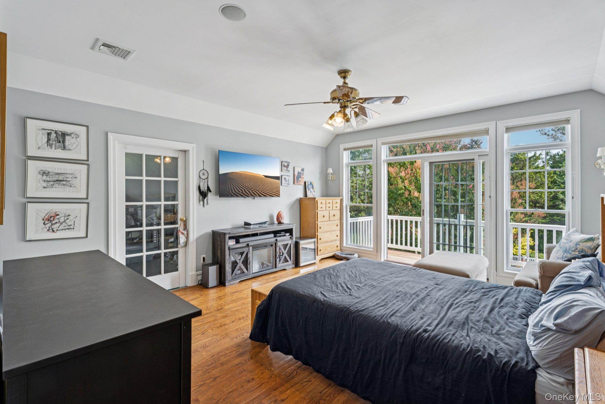 12 Laila Lane Remsenburg, NY 11960 - Photo 29 of 50 a bedroom with a large bed a flat tv screen and a dresser