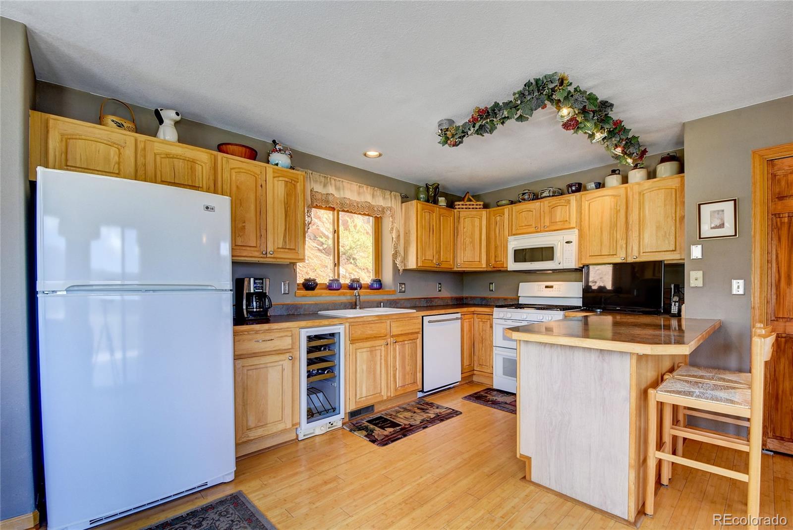 33633 Elk Run Evergreen, CO 80439 - Photo 16 of 40 a kitchen with a refrigerator a stove top oven a sink dishwasher and wooden cabinets