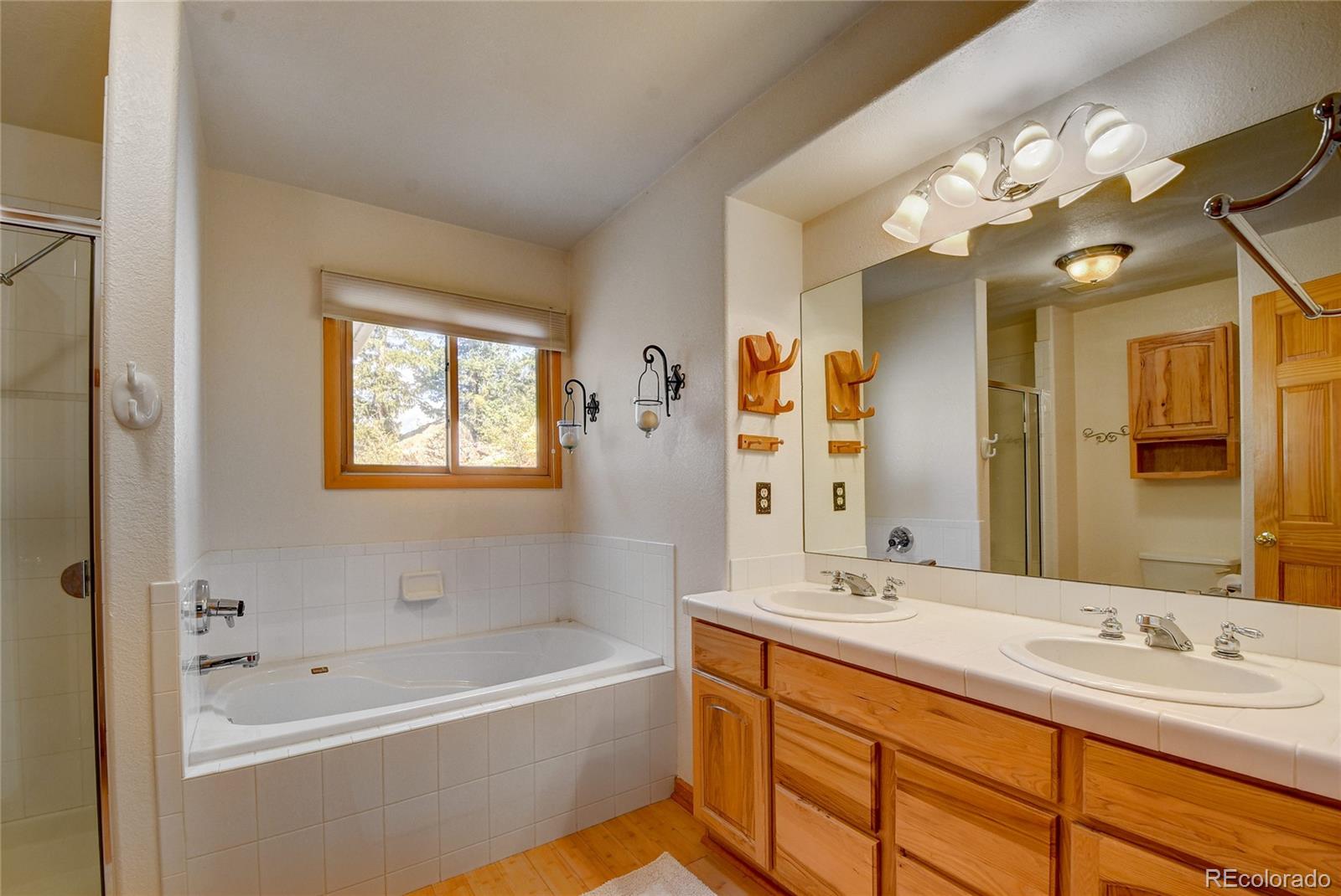 33633 Elk Run Evergreen, CO 80439 - Photo 19 of 40 a bathroom with a tub a sink double vanity and a mirror