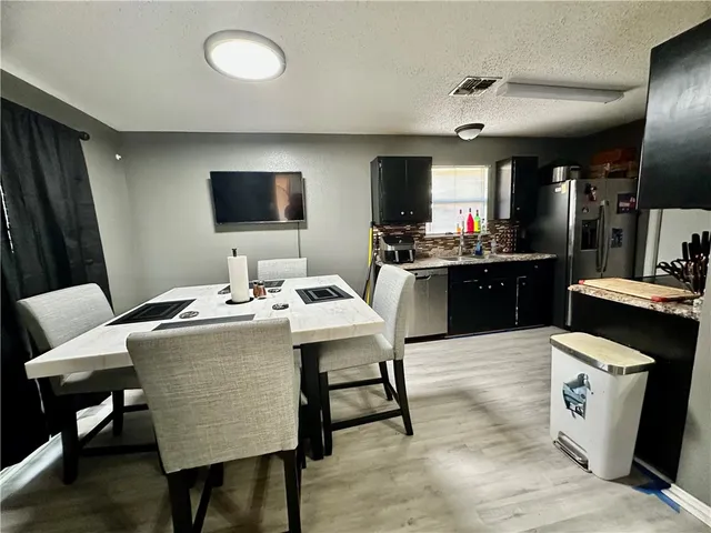 a kitchen with a table chairs refrigerator and microwave