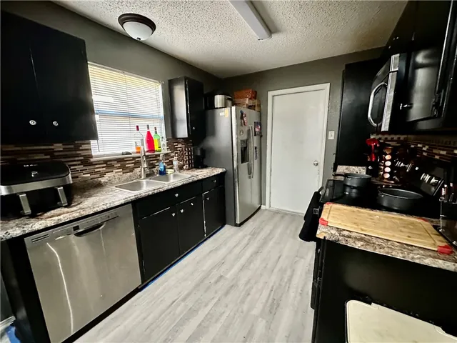 a kitchen with stainless steel appliances granite countertop sink stove and refrigerator