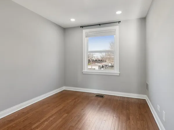 a view of an empty room with wooden floor and a bathroom