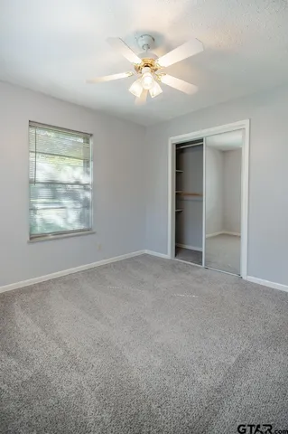 an empty room with windows and fan