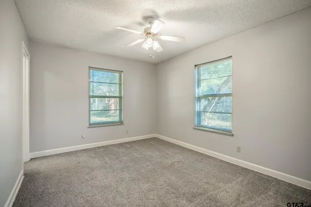 an empty room with windows and chandelier fan
