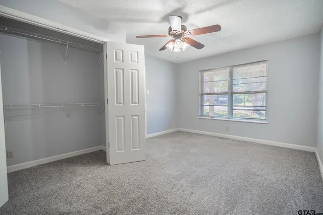 an empty room with windows and fan