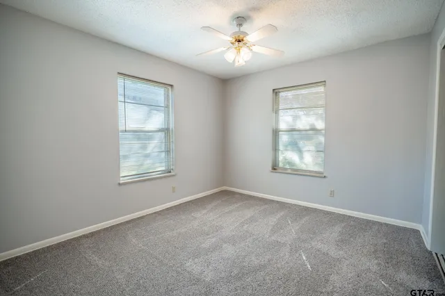 an empty room with windows and ceiling fan