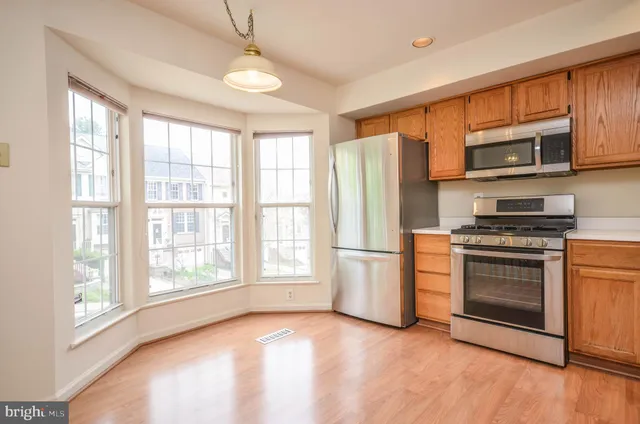 a kitchen with stainless steel appliances granite countertop a refrigerator a stove a sink and a window