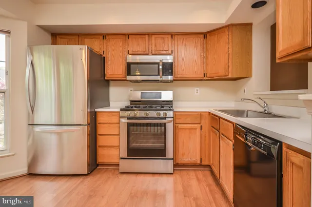 a kitchen with granite countertop a refrigerator stove and microwave with wooden floor