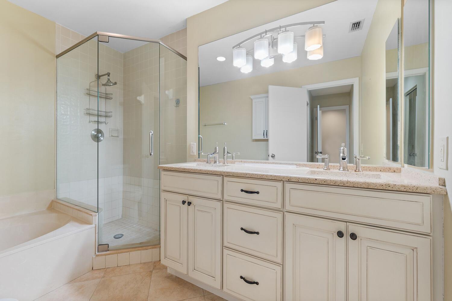 103 Half Moon Circle, Unit D2 Hypoluxo, FL 33462 - Photo 11 of 26 a bathroom with a double vanity sink mirror and a bathtub