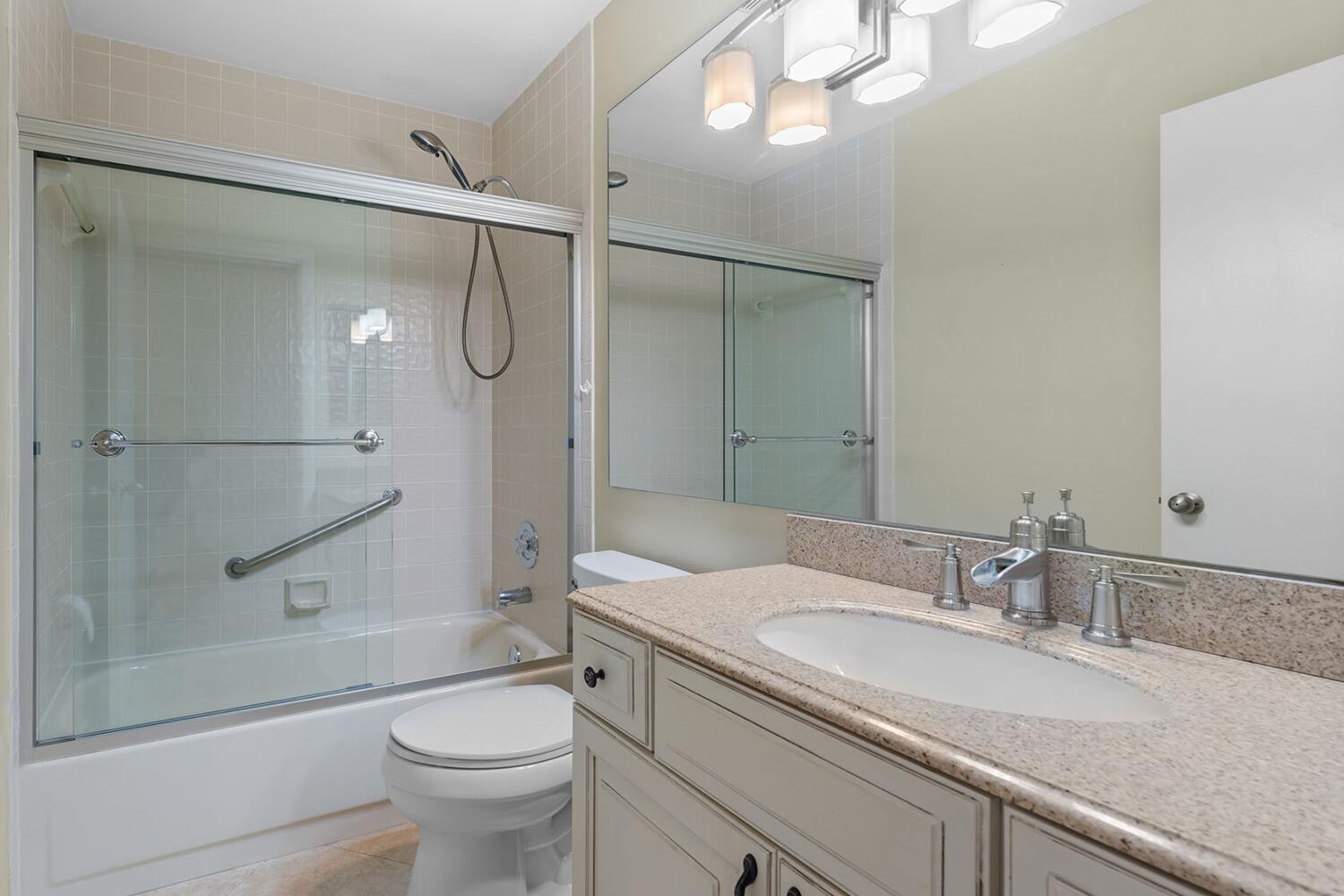 103 Half Moon Circle, Unit D2 Hypoluxo, FL 33462 - Photo 12 of 26 a bathroom with a granite countertop sink a toilet and shower