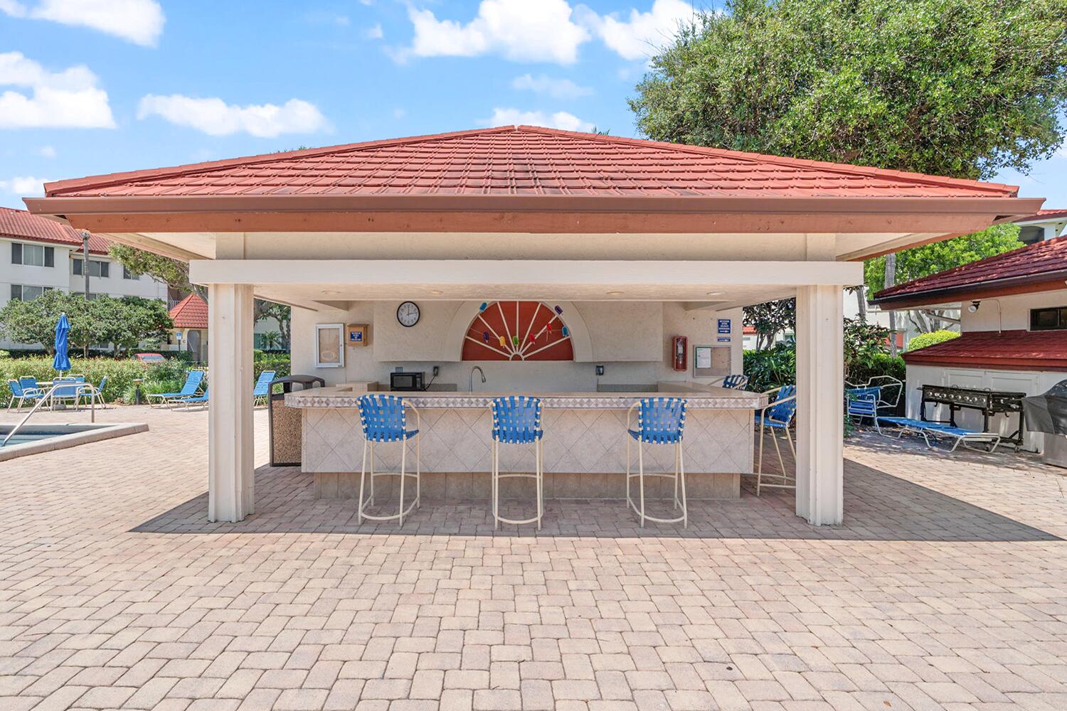 103 Half Moon Circle, Unit D2 Hypoluxo, FL 33462 - Photo 18 of 26 a view of a patio with table and chairs potted plants with palm trees