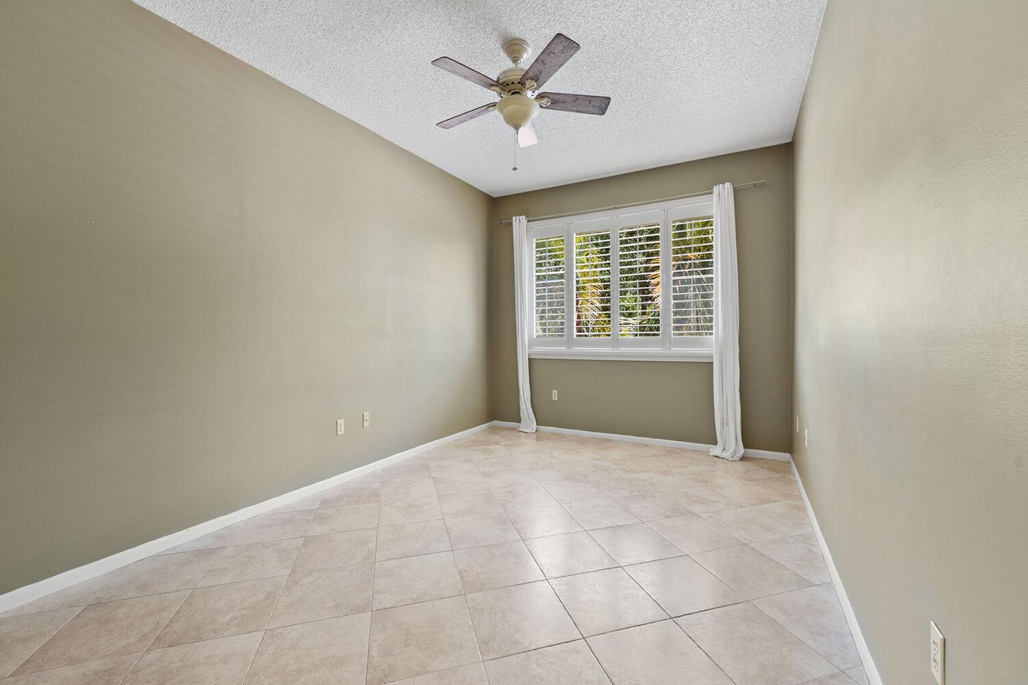 103 Half Moon Circle, Unit D2 Hypoluxo, FL 33462 - Photo 8 of 26 an empty room with chandelier fan and windows