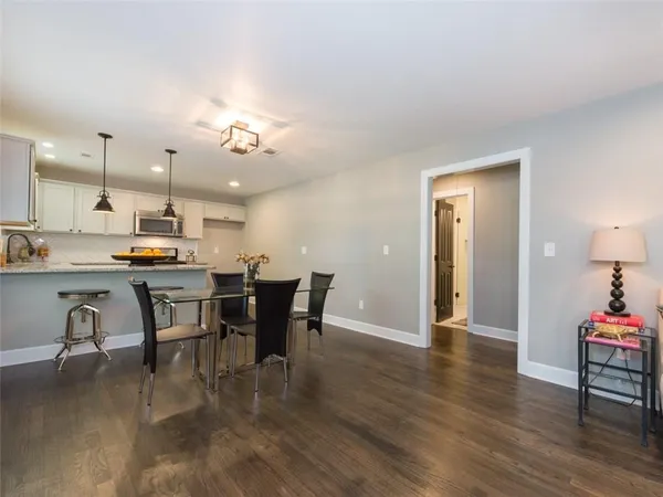 a open dining room with kitchen island stainless steel appliances furniture a dining table and chairs with wooden floor