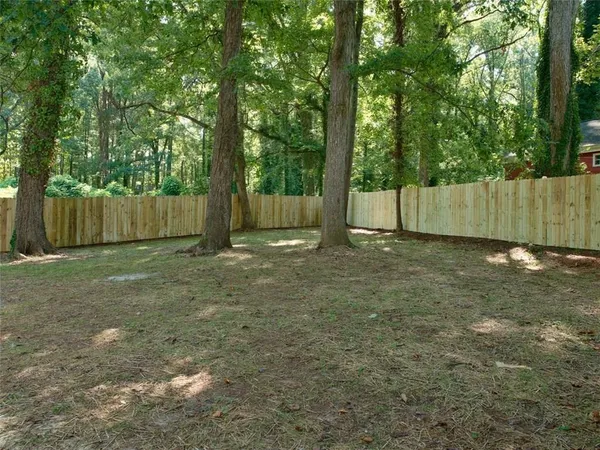 a view of backyard with green space and wooden fence