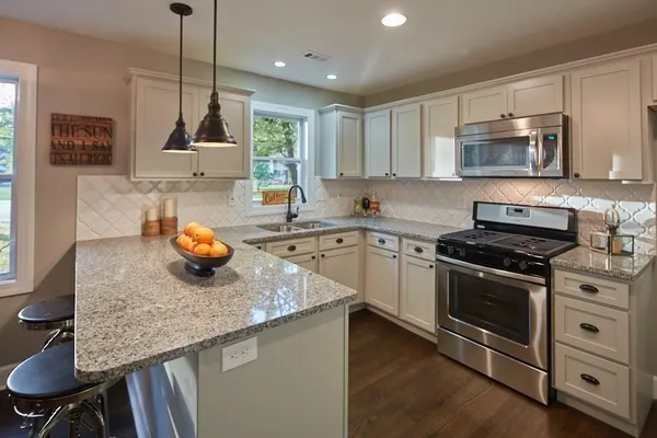 a kitchen with stainless steel appliances granite countertop a sink a stove and a wooden floors