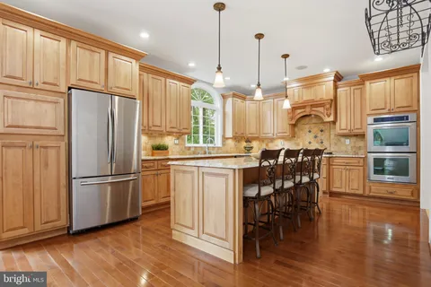 a kitchen with stainless steel appliances granite countertop a refrigerator a oven a sink a dining table and chairs with wooden floor