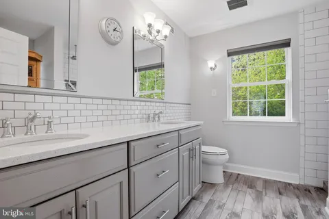 a bathroom with a granite countertop sink a toilet and a window