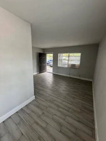 a view of an empty room with window and wooden floor