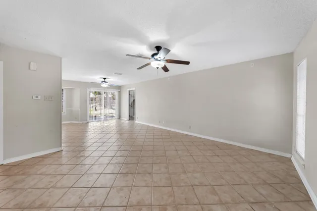 a view of an empty room with a ceiling fan and window