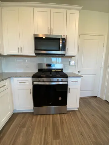 a kitchen with stainless steel appliances a stove a microwave and white cabinets