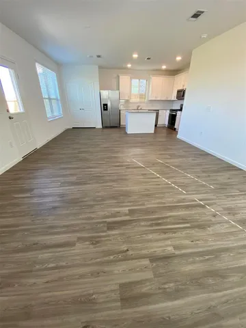 a view of a kitchen with kitchen island a sink wooden floor and a counter top space