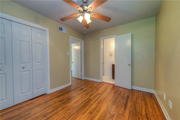 a view of a room with wooden floor and a ceiling fan