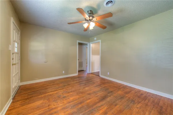 a view of an empty room with window and wooden floor