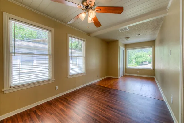 a view of an empty room with wooden floor and a window