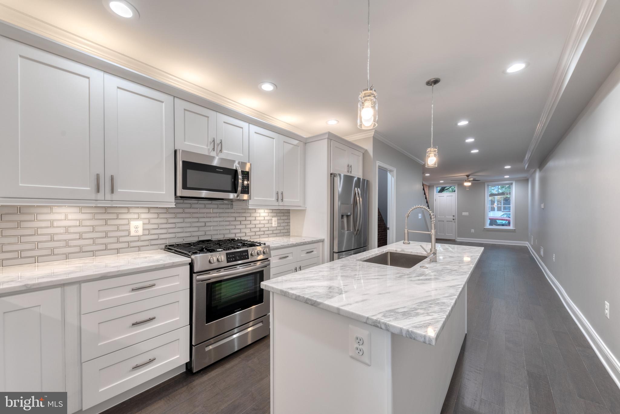 a kitchen with kitchen island granite countertop stainless steel appliances and white cabinets