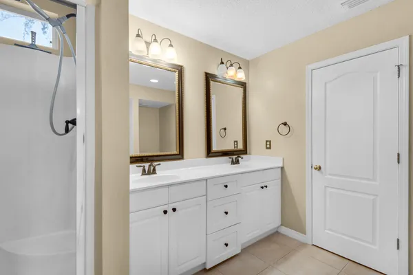 a bathroom with a granite countertop sink a mirror and shower