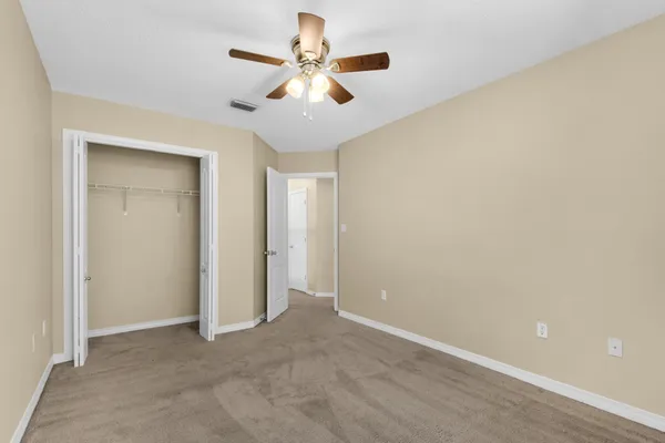 an empty room with closet and fan